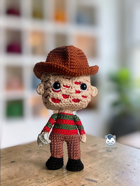 Amigurumi de Freddy Krueger tejido a crochet con sombrero marrón y jersey rojo y verde, patrón digital PDF para fans del cine de terror y muñecos estilo Funko