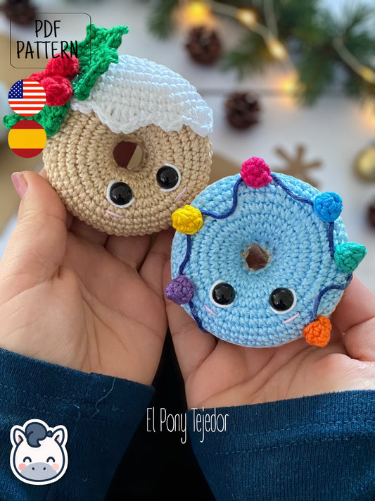 Patrón de ganchillo amigurumi de dos donuts navideños: uno beige con glaseado blanco y acebo, y otro azul con una guirnalda de luces de colores. Crochet amigurumi pattern of two Christmas donuts: one beige with white icing and holly, and one blue with a colorful string of Christmas lights