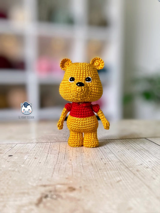 Patrón amigurumi inspirado en Winnie the Pooh tejido a crochet. Osito de ganchillo con camiseta roja, ideal para crear un adorable muñeco amigurumi con patrón PDF paso a paso.