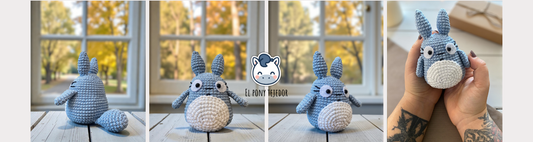 Blue and white crochet Totoro amigurumi on a wooden table with a blurry autumn forest background.