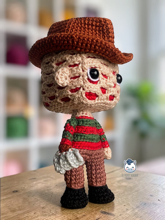 Amigurumi de Freddy Krueger tejido a crochet con sombrero marrón y jersey rojo y verde, patrón digital PDF para fans del cine de terror y muñecos estilo Funko