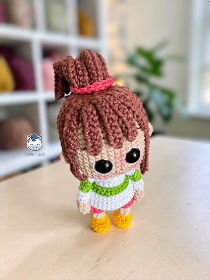 Amigurumi de Chihiro inspirado en El Viaje de Chihiro, con su característica coleta, jersey a rayas y pantalones rosas. Un patrón de crochet perfecto para fans de Studio Ghibli, amantes del anime japonés, coleccionistas geek y aficionados a los amigurumis hechos a mano.