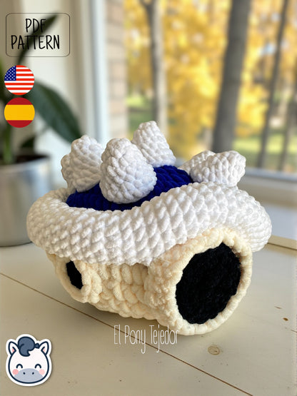 Amigurumi de la Concha Azul con pinchos de Mario Kart tejido a ganchillo en lana suave blanca y azul.
Crochet Amigurumi of the Blue Spiny Shell from Mario Kart made with soft blue and white yarn.