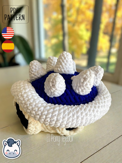 Amigurumi de la Concha Azul con pinchos de Mario Kart tejido a ganchillo en lana suave blanca y azul.
Crochet Amigurumi of the Blue Spiny Shell from Mario Kart made with soft blue and white yarn.
