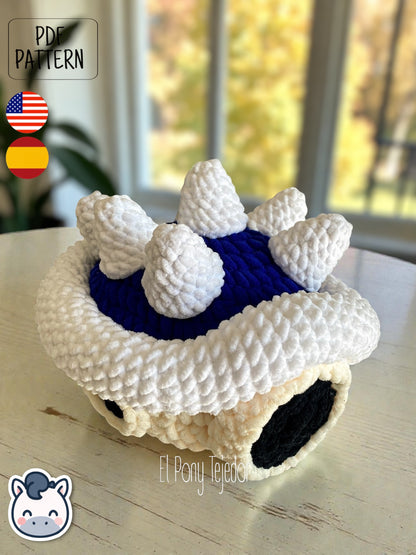 Amigurumi de la Concha Azul con pinchos de Mario Kart tejido a ganchillo en lana suave blanca y azul.
Crochet Amigurumi of the Blue Spiny Shell from Mario Kart made with soft blue and white yarn.