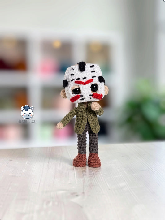 Amigurumi de Jason Voorhees hecho a mano a ganchillo, inspirado en Viernes 13, con su icónica máscara blanca de hockey, chaqueta verde y pantalones oscuros. Patrón PDF de crochet ideal para Halloween y coleccionistas del cine de terror.