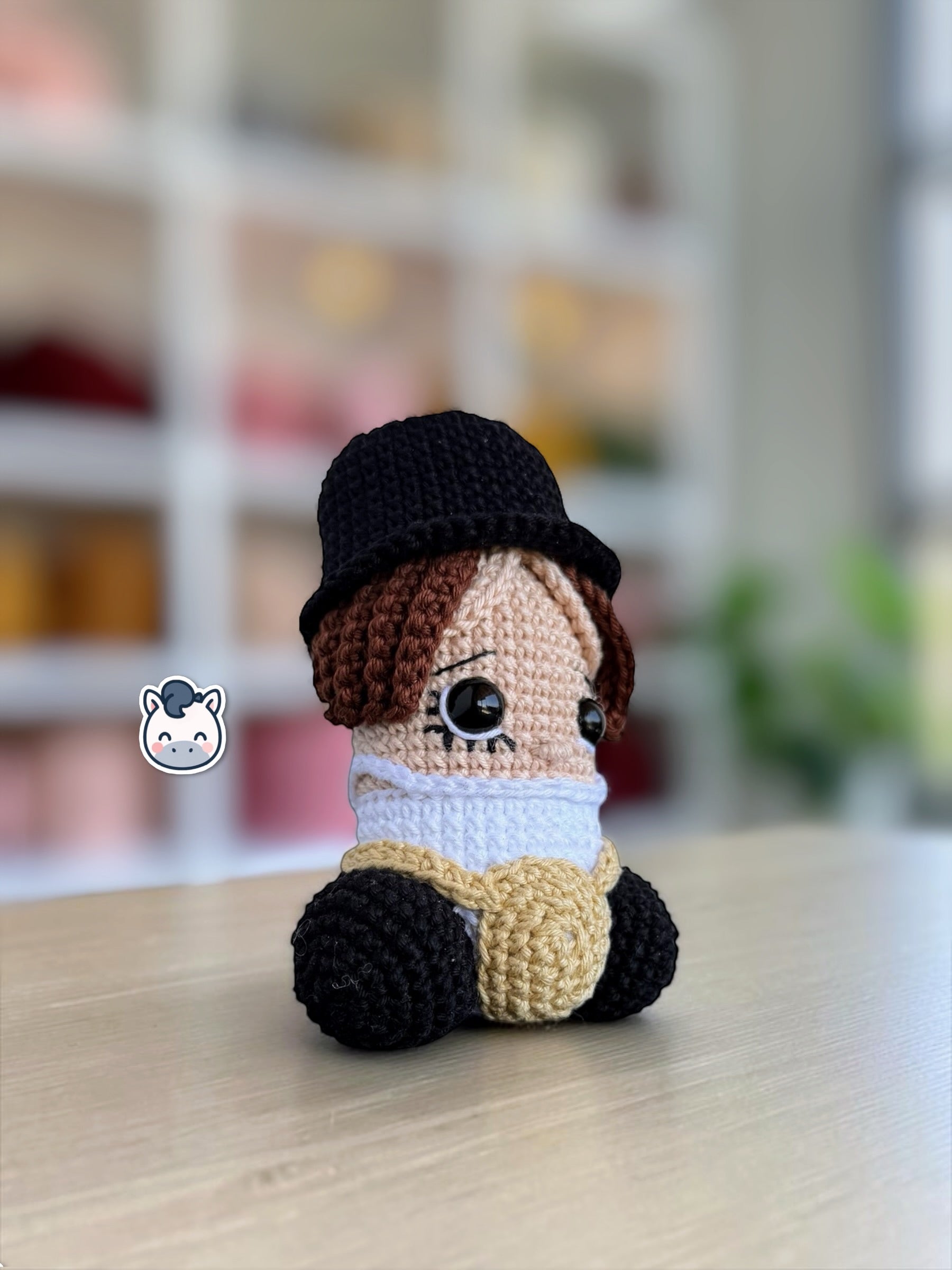 Muñeco amigurumi de Pene hecho a mano a crochet, inspirado en el personaje de La Naranja Mecánica. Peluche artesanal tejido con hilo de algodón, con sombrero negro y detalles característicos de la película. Ideal para coleccionistas de cine, decoración geek y amantes de las películas de culto.