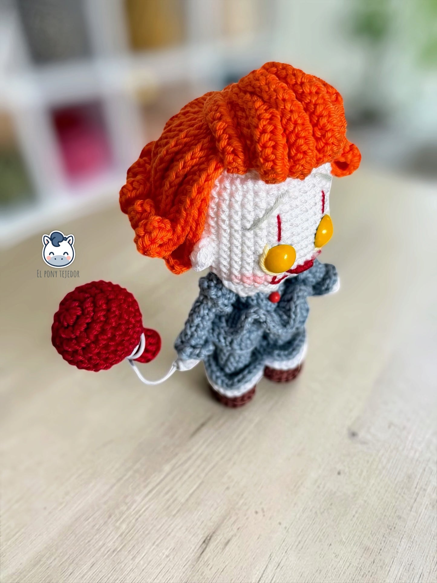 Amigurumi de Pennywise inspirado en IT, un patrón PDF de crochet con estilo Funko y su icónico globo rojo, perfecto para fans del cine de terror y la decoración de Halloween.