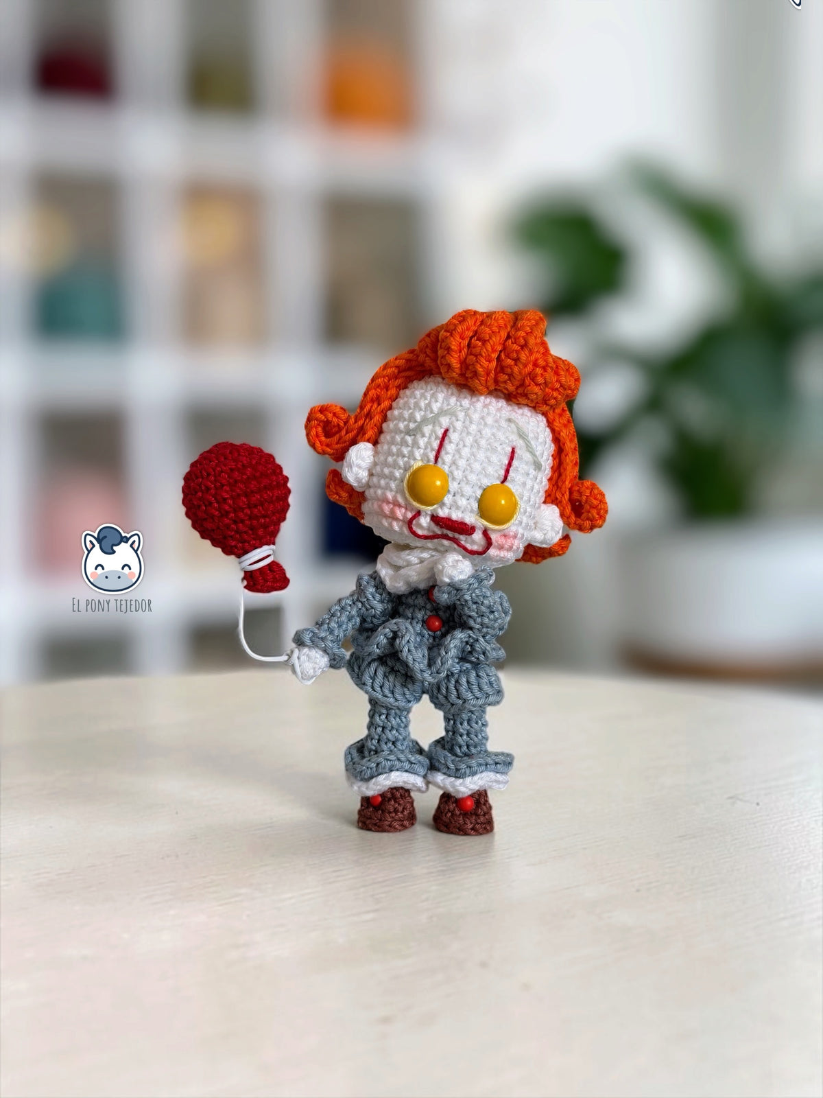 Amigurumi de Pennywise inspirado en IT, un patrón PDF de crochet con estilo Funko y su icónico globo rojo, perfecto para fans del cine de terror y la decoración de Halloween.