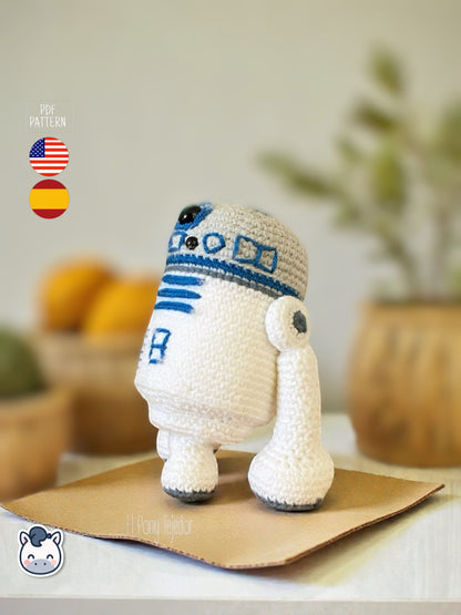 Patrón de ganchillo Amigurumi de R2-D2 tejido en color blanco y azul, inspirado en Star Wars, con detalles bordados y forma compacta.