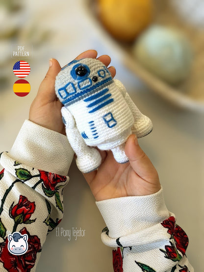 Patrón de ganchillo Amigurumi de R2-D2 tejido en color blanco y azul, inspirado en Star Wars, con detalles bordados y forma compacta.