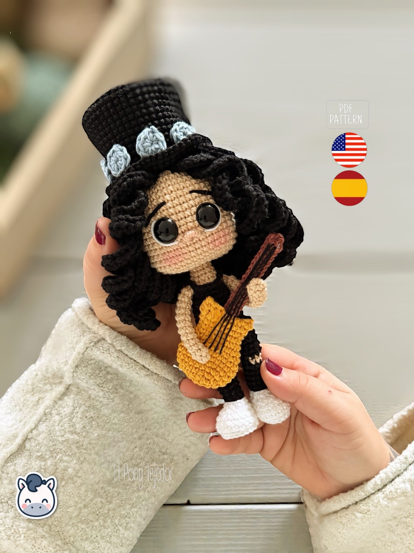 Patrón de ganchillo amigurumi de Slash con sombrero de copa negro, pelo rizado y guitarra amarilla, tejido a mano.
Slash amigurumi crochet pattern with black top hat, curly hair and yellow guitar, handmade design.