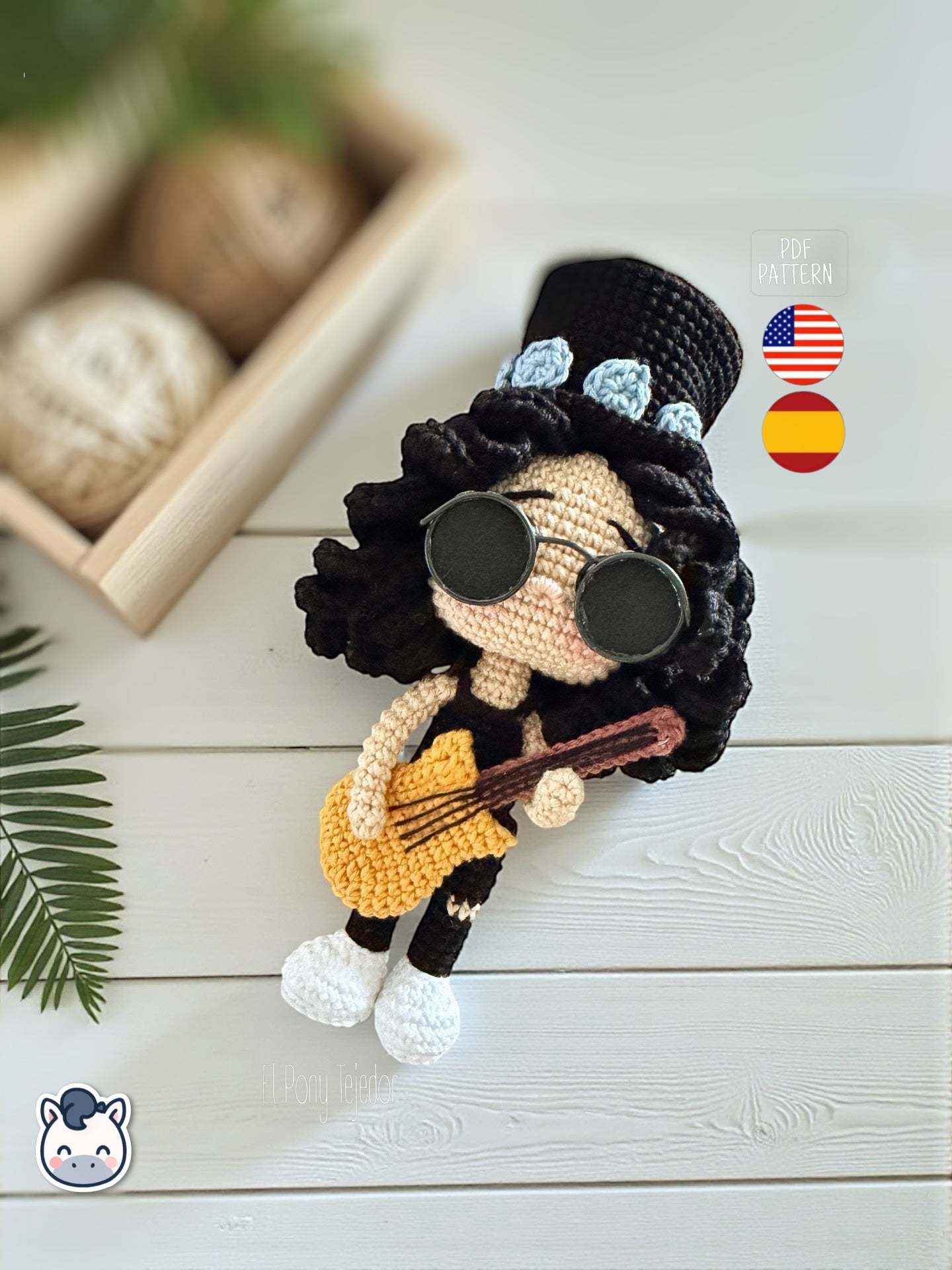 Patrón de ganchillo amigurumi de Slash con sombrero de copa negro, pelo rizado y guitarra amarilla, tejido a mano.
Slash amigurumi crochet pattern with black top hat, curly hair and yellow guitar, handmade design.