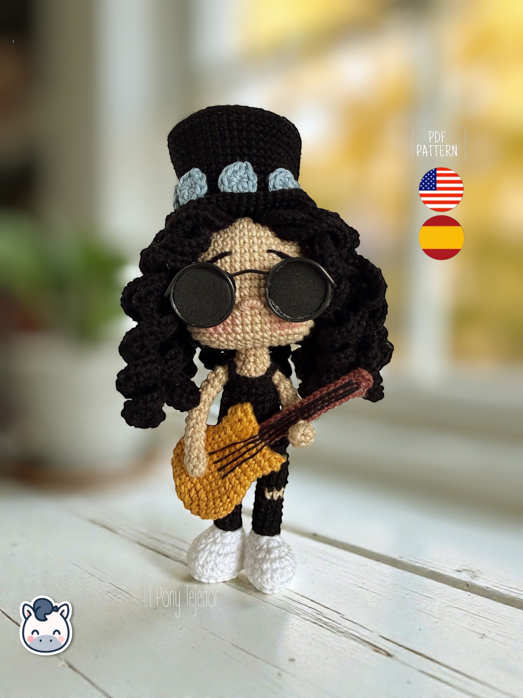 Patrón de ganchillo amigurumi de Slash con sombrero de copa negro, pelo rizado y guitarra amarilla, tejido a mano.
Slash amigurumi crochet pattern with black top hat, curly hair and yellow guitar, handmade design.