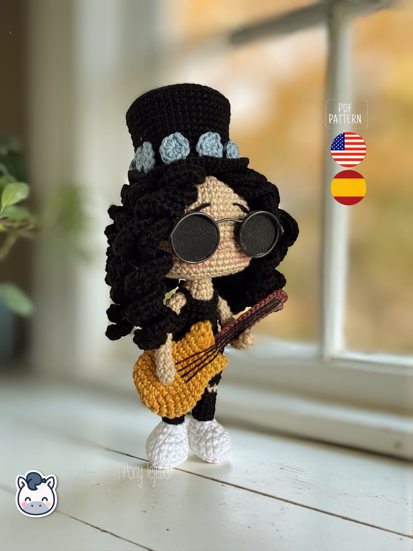 Patrón de ganchillo amigurumi de Slash con sombrero de copa negro, pelo rizado y guitarra amarilla, tejido a mano.
Slash amigurumi crochet pattern with black top hat, curly hair and yellow guitar, handmade design.