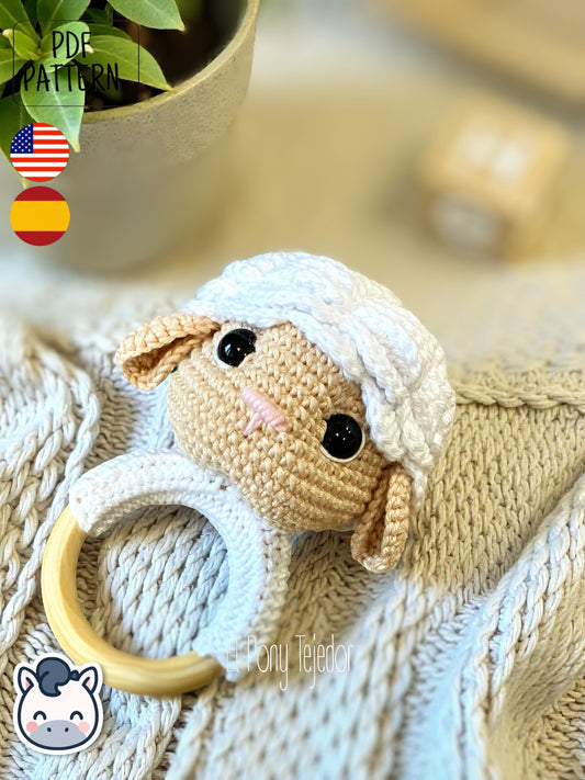 Sonajero de oveja tejido a ganchillo con cabeza de amigurumi blanca y beige sobre aro de madera natural.
Crochet sheep baby rattle with white and beige amigurumi head on a natural wooden ring.