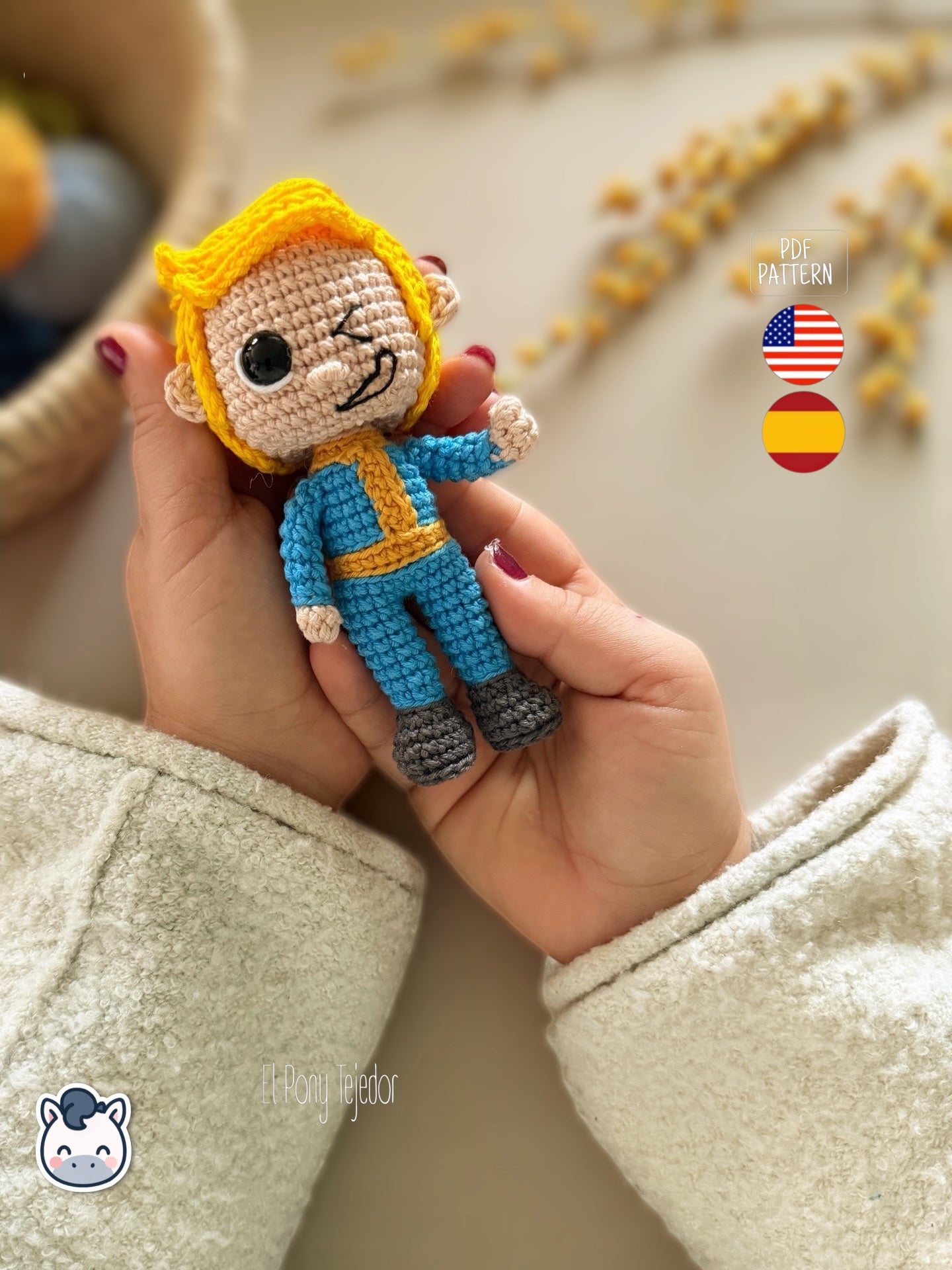 Patrón de ganchillo amigurumi de Vault Boy de Fallout con mono azul y expresión sonriente.
Vault Boy Fallout amigurumi crochet pattern with blue jumpsuit and smiling expression.