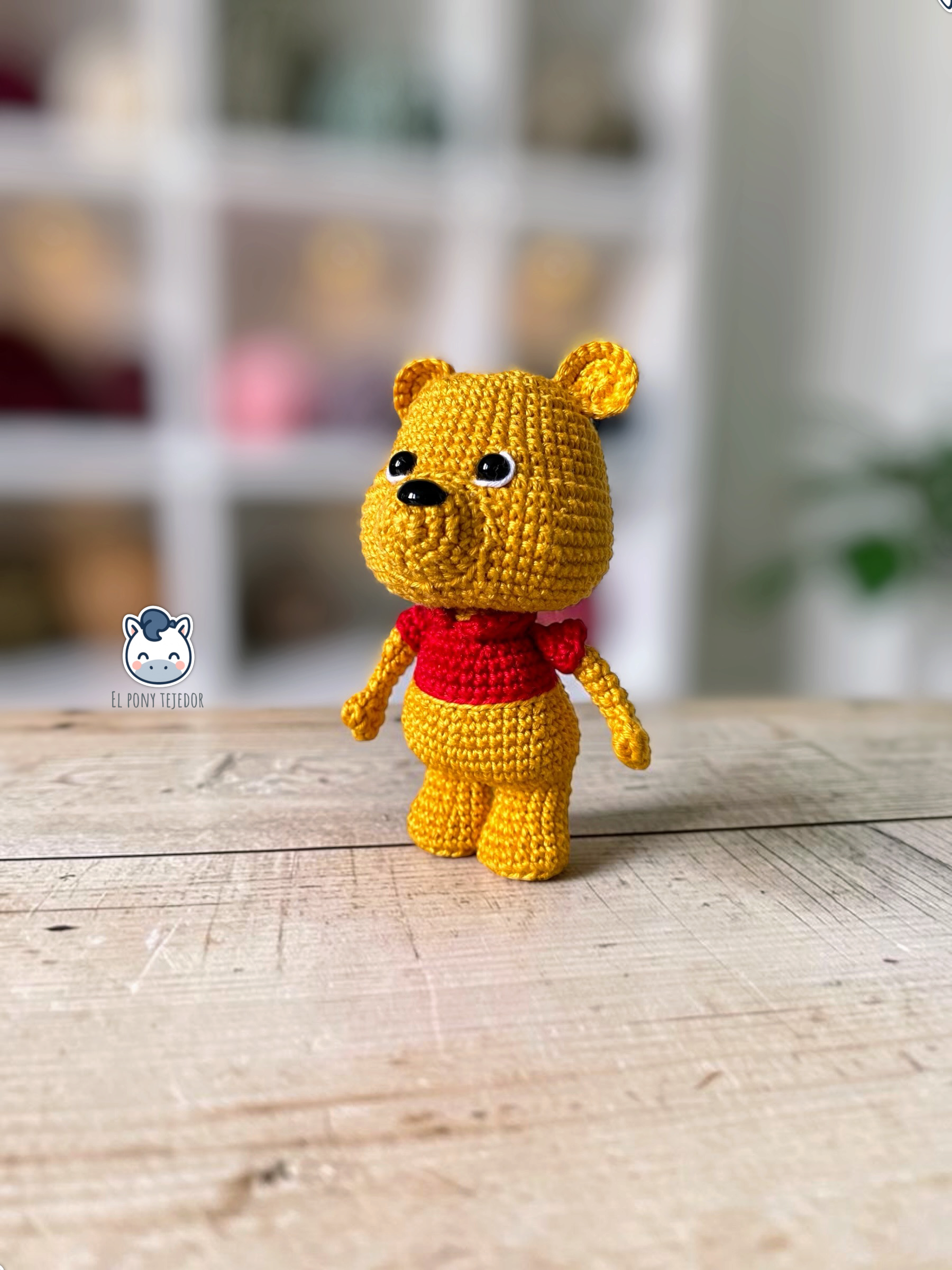 Patrón amigurumi inspirado en Winnie the Pooh tejido a crochet. Osito de ganchillo con camiseta roja, ideal para crear un adorable muñeco amigurumi con patrón PDF paso a paso.