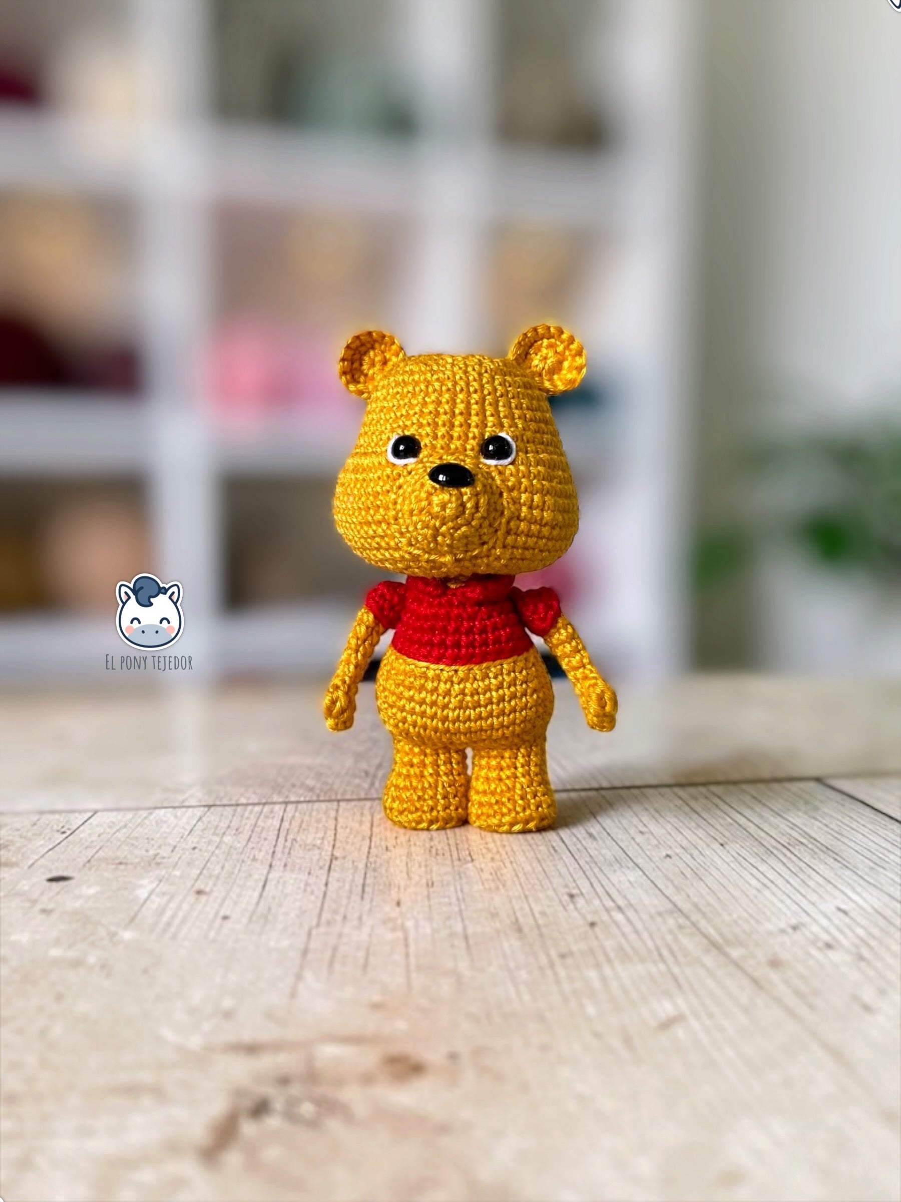 Patrón amigurumi inspirado en Winnie the Pooh tejido a crochet. Osito de ganchillo con camiseta roja, ideal para crear un adorable muñeco amigurumi con patrón PDF paso a paso.