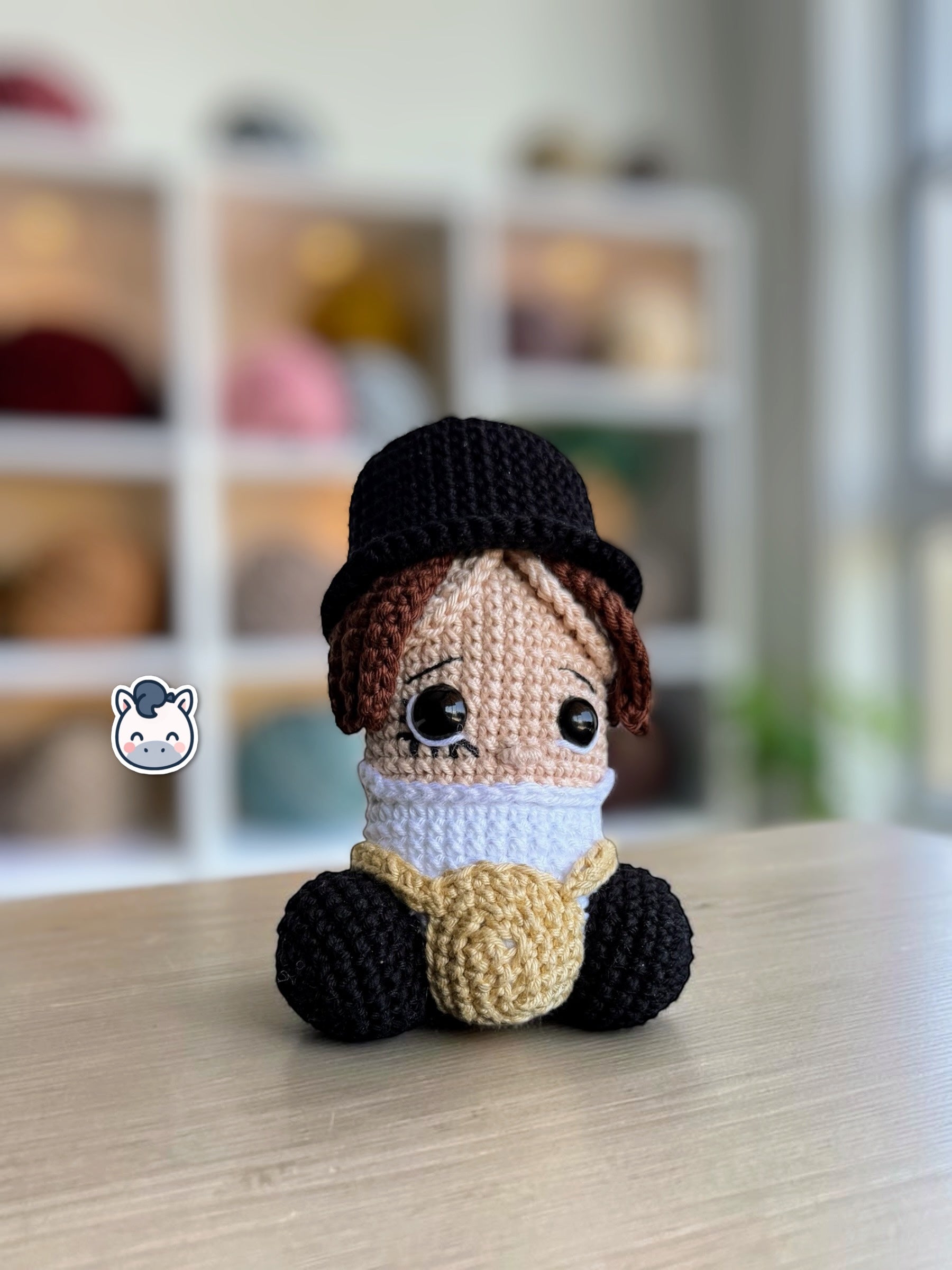 Muñeco amigurumi de Pene hecho a mano a crochet, inspirado en el personaje de La Naranja Mecánica. Peluche artesanal tejido con hilo de algodón, con sombrero negro y detalles característicos de la película. Ideal para coleccionistas de cine, decoración geek y amantes de las películas de culto.