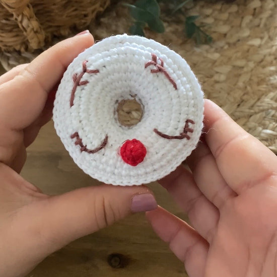VIdeo Tutorial Patrón de ganchillo Amigurumi de dos donuts navideños: uno de color verde menta con un copo de nieve blanco y otro blanco con cara de reno y nariz roja.  Crochet Amigurumi pattern of two Christmas donuts: one mint green with a white snowflake and one white with a reindeer face and red nose.